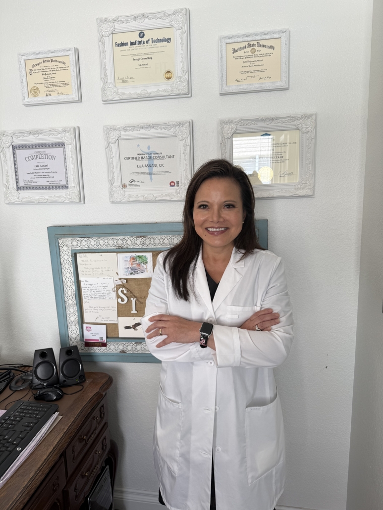 Lila Asnani in a lab coat standing in front of her degrees and certifications on the wall